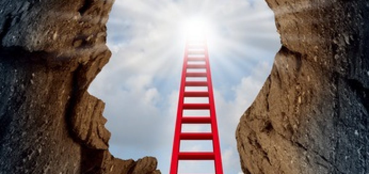 Concept of open mind as a a deep mountain cliff shaped as a human head with a ladder leading to the outside towards a glowing sun as a psychology and mental health metaphor for spiritual discovery.