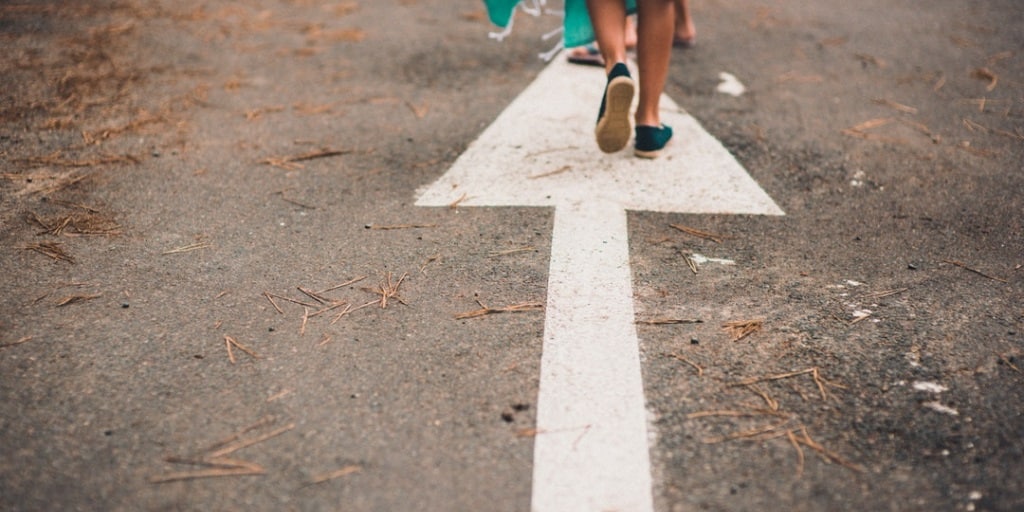 Advancement. Person walking on an arrow pointing forward.