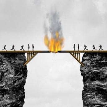 Burning bridge concept as groups of people divided by a wooden bridge on fire as a business connection risk metaphor for destroying a link or isolationism with 3D illustration elements.