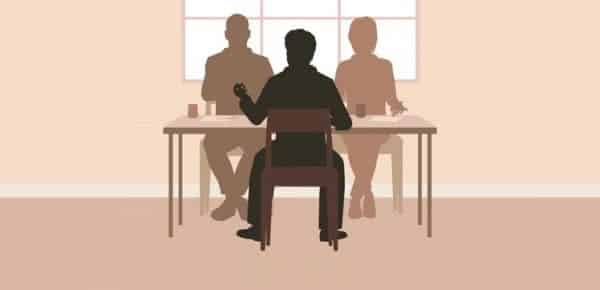 Silhouettes of people sitting at a table holding a discussion