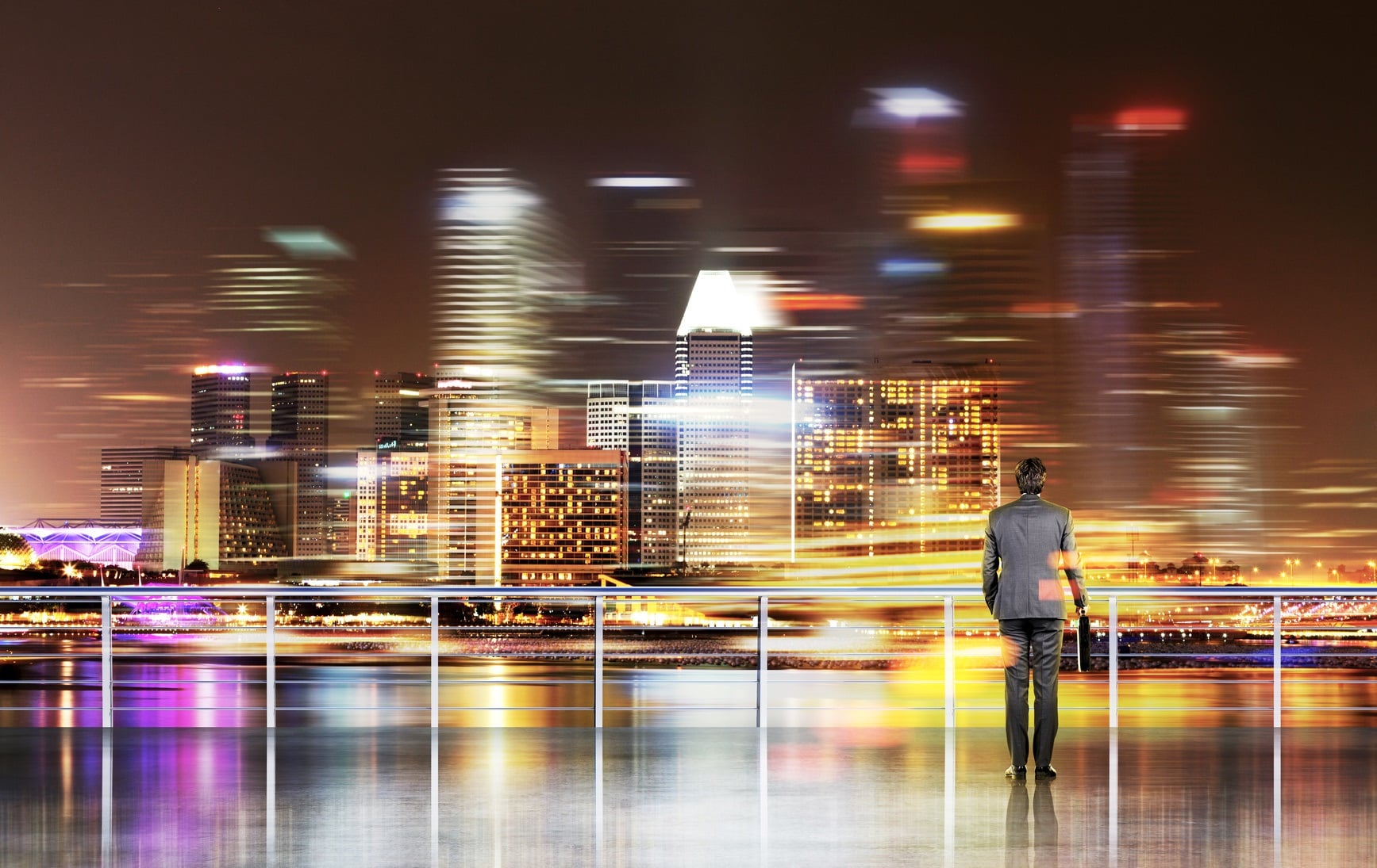 Businessman with hands in pockets, New York view at night. Enbankment. Double exposure. Concept of work.