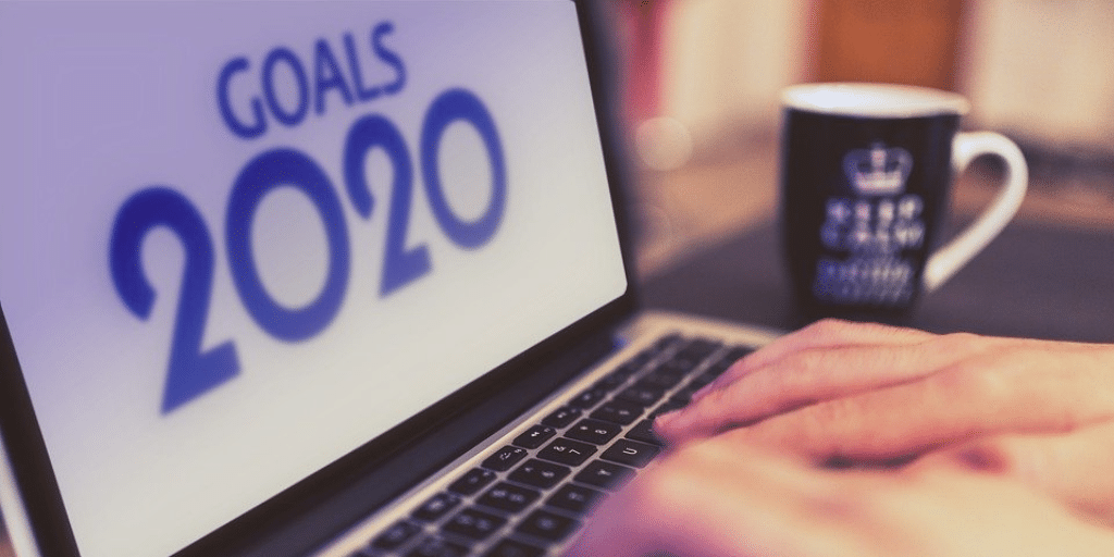 Hands typing on a laptop whose screen reads Goals 2020