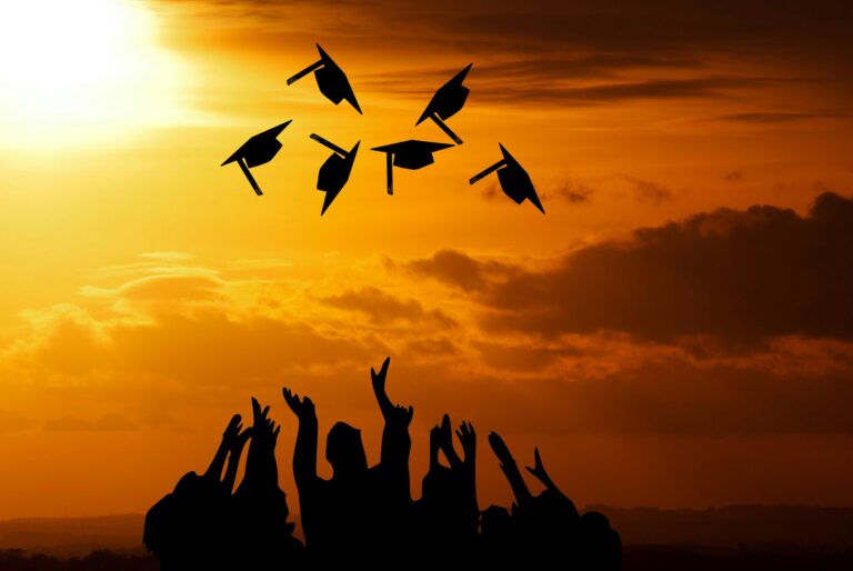 Silhouette of students throwing graduation caps in the air.