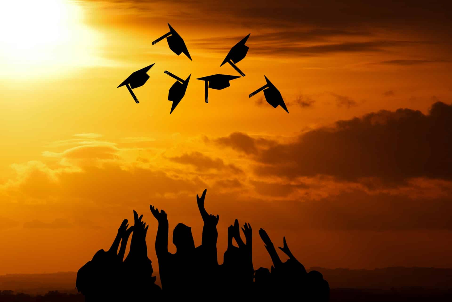 Silhouette of students throwing graduation caps in the air.