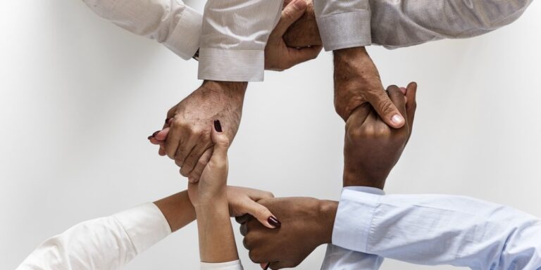A group of four people interlocking hands in a circle pattern