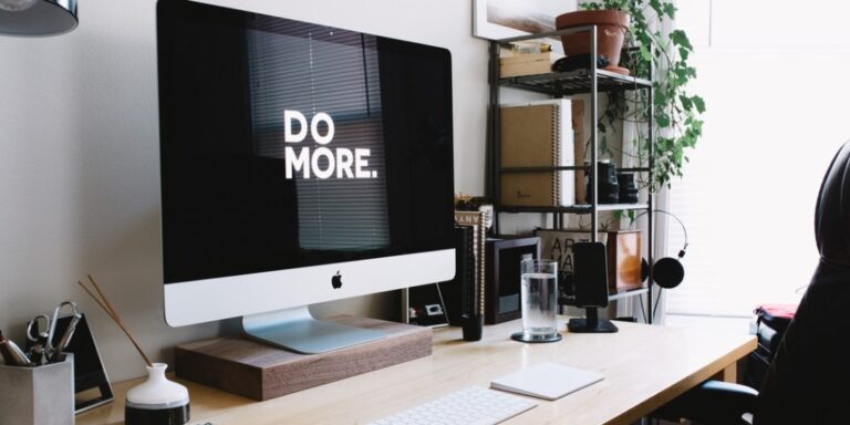 A neat and tidy desk with the words "Do More" displayed on a computer monitor