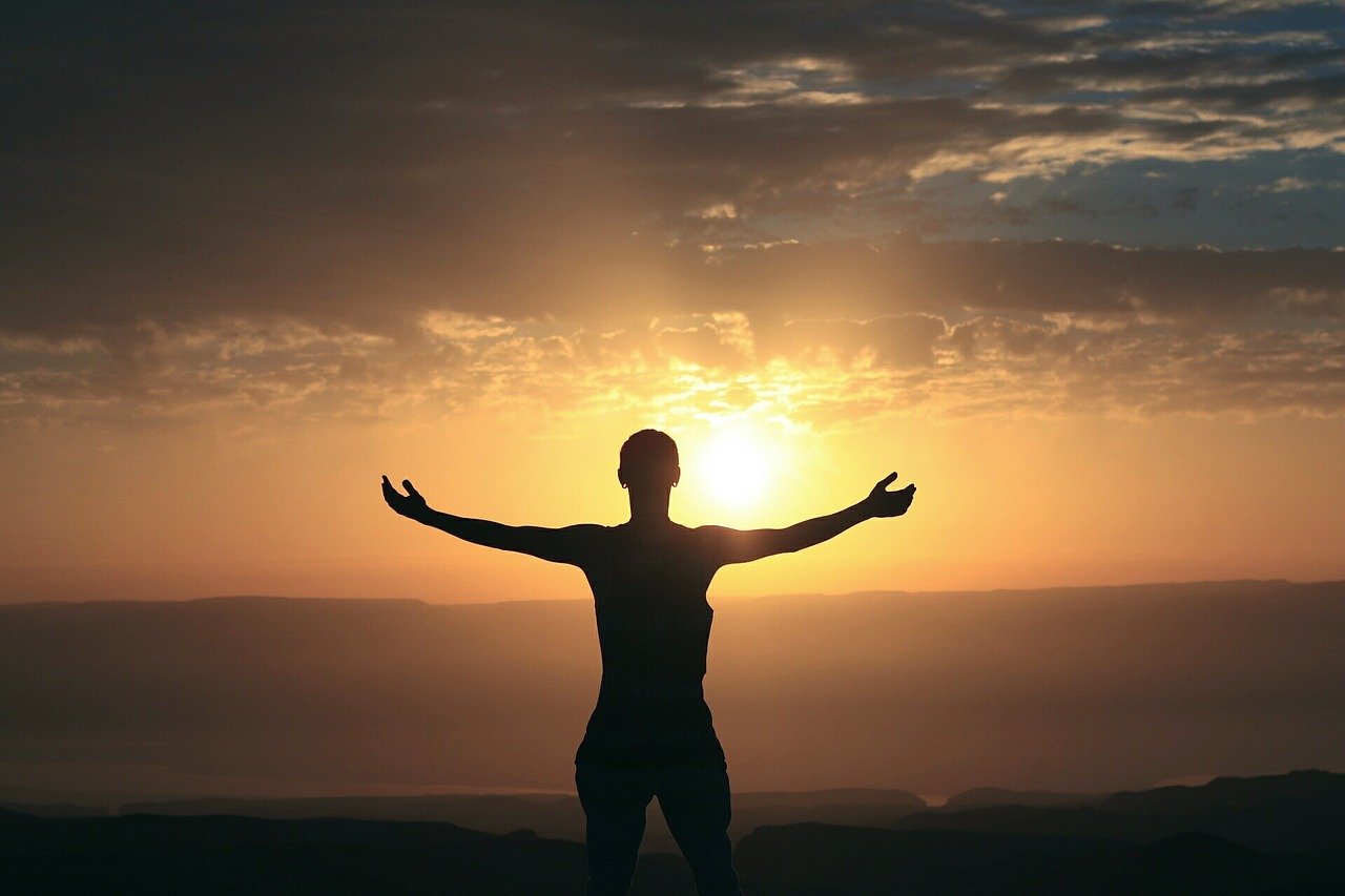 A woman, with arms spread, welcoming a sunrise. Meant to depict being thankful.