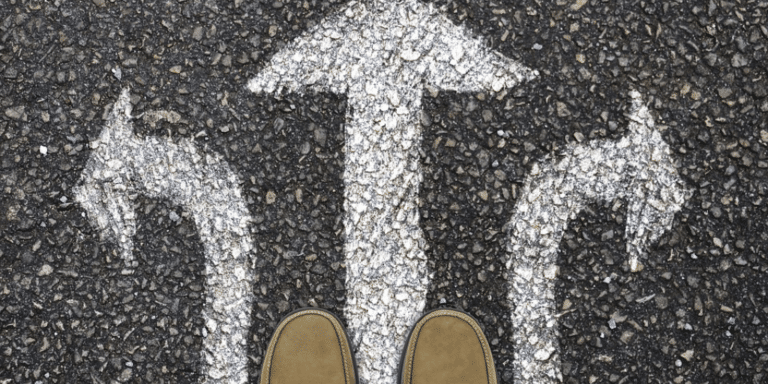 A pair of shoes overlooking arrows painted on the ground facing left, right, and forward
