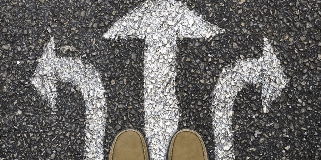 A pair of shoes overlooking arrows painted on the ground facing left, right, and forward