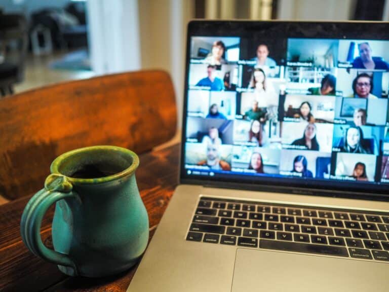 A coffee mug sat next to an open laptop which is displaying a virtual conference