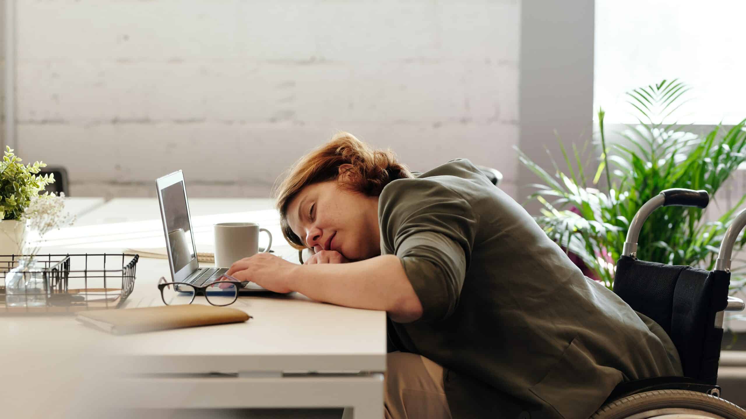 A woman sleeping at her desk. An image meant to depict procrastination.