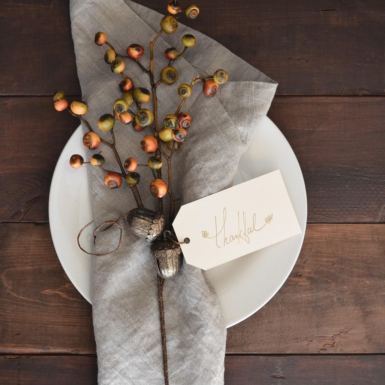 a plate with a napkin and tag on it that reads thankful
