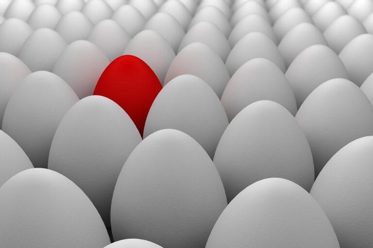 One red egg amidst a bunch of white ones.