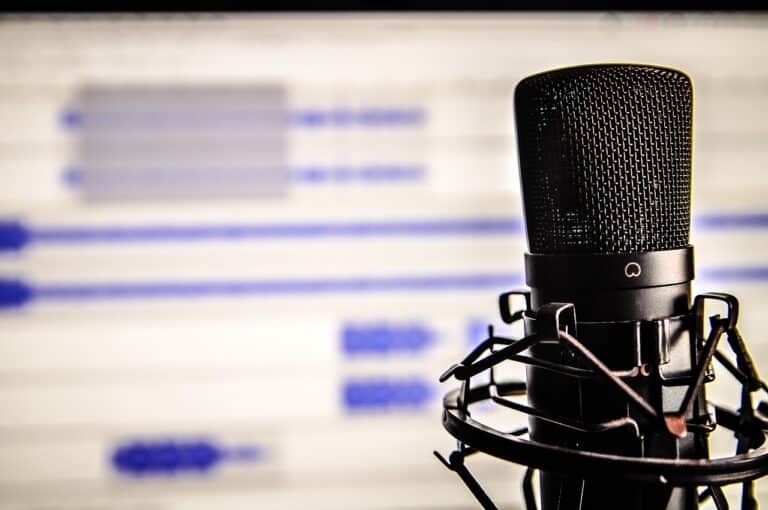 An image of a microphone in front of a computer screen.